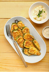 Plate with delicious jalapeno poppers and sauce on wooden background