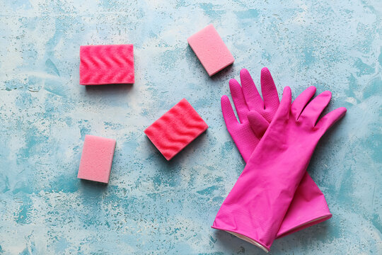 Pink Cleaning Sponges And Gloves On Grunge Color Background