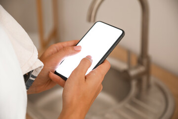 Woman using mobile phone in kitchen