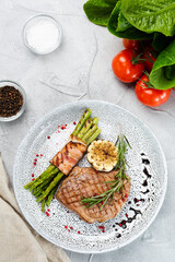 grilled steak with asparagus, rosemary leaf and grilled garlic on plate and ingredients with...