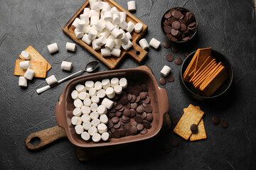 Ingredients for preparing S'mores dip on dark background