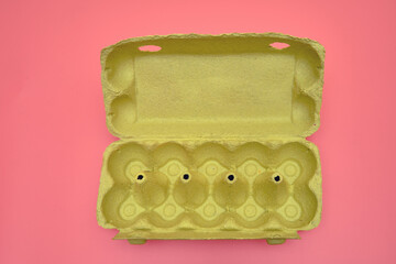Empty egg packaging in a cardboard box on a pink background