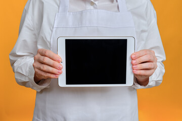 Man chef showing tablet screen on yellow studio background, mockup copy space