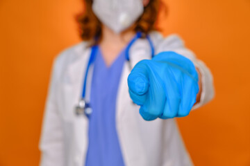 Hand in a medical glove points a finger at you, close up