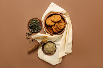 Bowl of hojicha cookies, powder and chasen on brown background