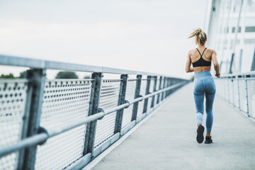 Obraz premium Muscular Woman Jogging On The Bridge