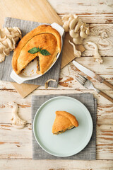 Baking dish and plate with tasty mushroom pot pie on white wooden background