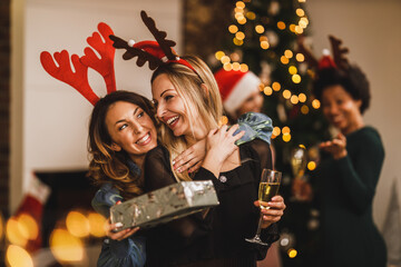 Female Friends Giving Gifts To Each Other During Christmas Party At Home