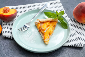 Plate with piece of tasty peach galette on dark background, closeup