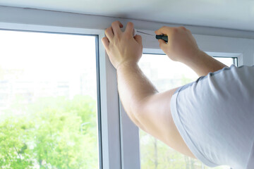 man worker hands installing attaching mounting bracket on roller blinds, shades, on plastic window...