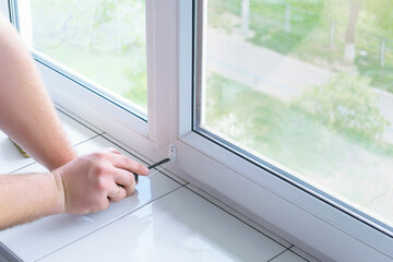 man worker hands installing attaching mounting bracket on roller blinds, shades, on plastic window...