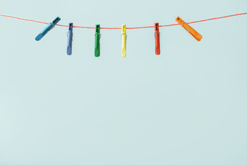 Many plastic clothespins hanging on rope against blue background