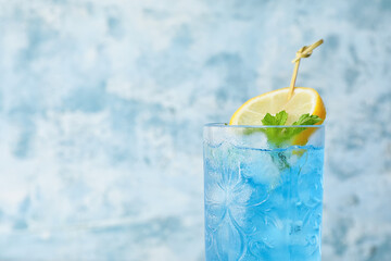 Glass of Blue Lagoon cocktail on color background, closeup