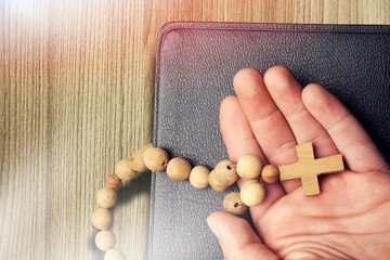 Humen christian read bible. Hands folded in prayer on a Holy Bible on wooden table.