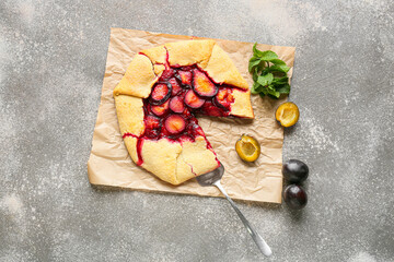 Parchment with tasty plum galette on grunge background