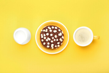 Plate with tasty chocolate cookie, milk and cup of coffee on yellow background