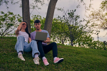 young couple looking a laptop and talking to friends