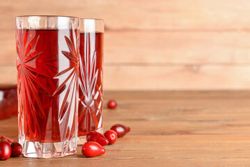 Glasses of healthy dogwood berry drink on wooden background © Pixel-Shot