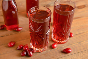 Glasses of healthy dogwood berry drink on wooden background © Pixel-Shot