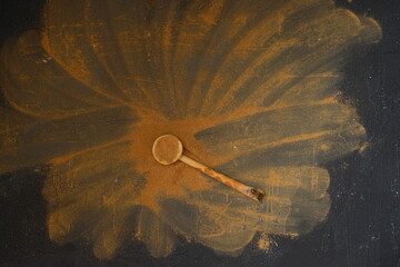 Cinnamon powder  and spoon on black background, top view