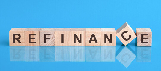 refinance word is made of wooden building blocks lying on the blue table, concept - obrazy, fototapety, plakaty