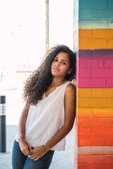 Portrait of a teenage Cuban girl leaning against a colorful wall, cuban latin teenager woman