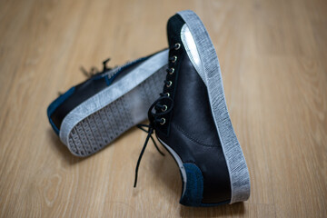 Selective focus shot of a pair of leather sneakers on the floor