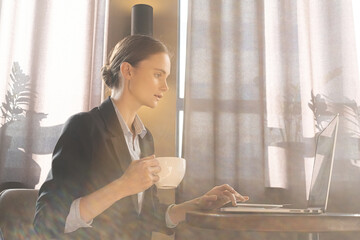 Girl freelancer working on a laptop in cafe. Work from home. Remote education