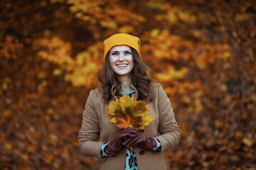 smiling elegant woman in beige coat and orange hat