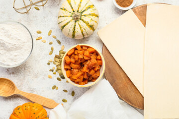 Raw dough and ingredients for preparing pumpkin strudel on light background