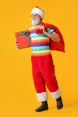 Cool Santa Claus with gift and bag on color background
