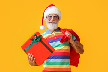 Cool Santa Claus with gift and bag on color background