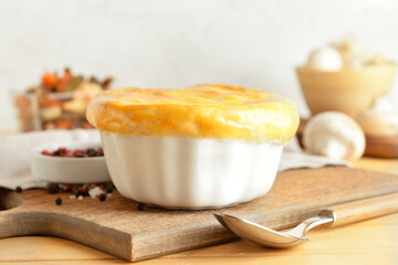 Wooden board with tasty vegetable pot pie on table