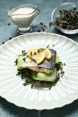 Plate of tasty sea bass fish on grey background