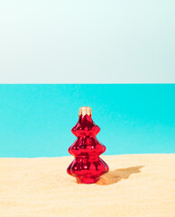 Red Christmas tree on tropical beach. Winter Christmas holiday concept. Happy New Year background. Minimal summer beach idea.