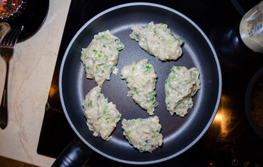 raw chicken mince patties with green on the blue iron pan top view