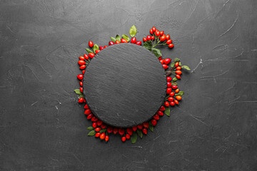 Composition with fresh rose hip berries on black background