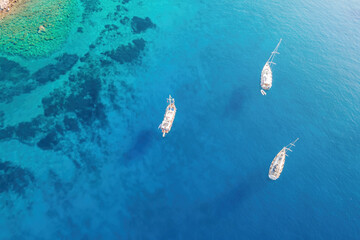 Yachts and sailing boatsin bay with a turquoise and transparent sea. Top view of the sailing boats in blue lagoon