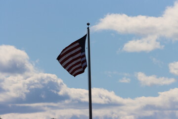 american flag waving against blue cloudy sky