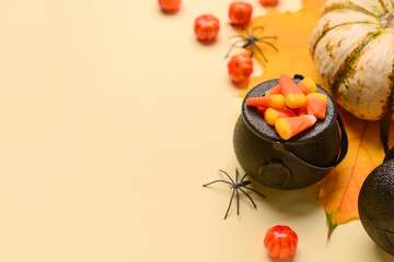 Witch's cauldron with candies and spider on beige background