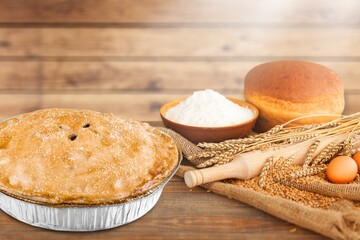 Naklejka premium Homemade round cake on the desk with ingredients: eggs, flour, milk