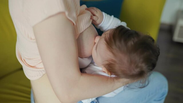 Close up of little newborn baby while sucking mothers breast milk. Woman breastfeeding newborn baby.