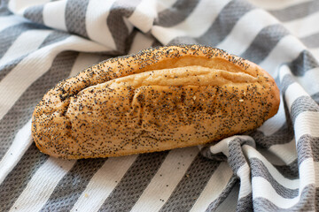 Loaf of White Bread with Poppy Seads on a gray and white stripe cloth