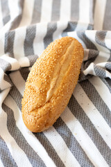 White Bread with Sesame Seeds on the table on a kitchen gray and white cloth