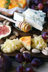 Cheese board with nuts, fruit and honey.