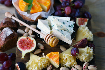 Cheese board with nuts, fruit and honey.