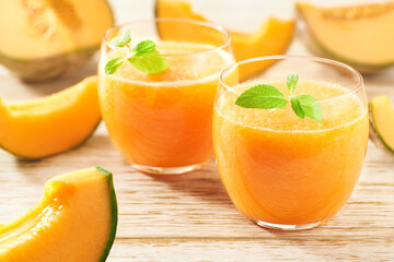 Homemade smoothie with fresh melon and mint on a wooden table.