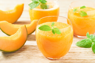 Homemade smoothie with fresh melon and mint on a wooden table, close up.