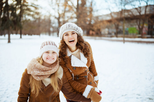 happy elegant mom and child outside in city park in winter