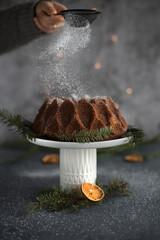 chocolate bundt cake on a white cakestand, dry orange, holy and christmas lights